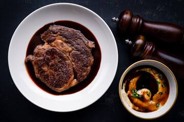 Top down view on delicious meat dinner in dark round plate with copy space over wooden table