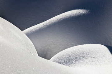 beautiful smooth lines texture of snowdrifts play of light and shadow of a winter landscape on the background