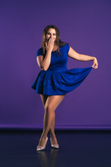 Happy plus size model in blue dress on purple background