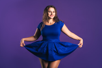 Happy plus size model in blue dress on purple background