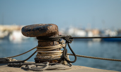 A rusty bollard with ropes. Fishing boats moor here in the port of Santa Pola in Spain. The...