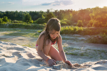 A little girl is building a beach sand castle. Active lifestyle, games, vacations, vacations, rest.