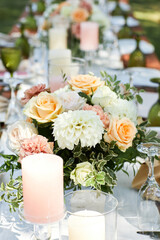 long dinner tables with white cloth, served with porcelains. Georgeous wedding table decorated with flowers and candles