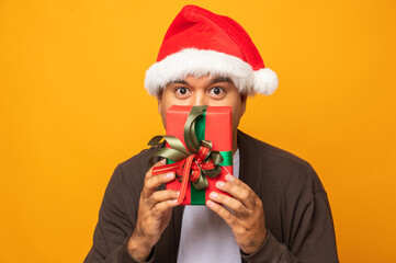 Funny asian man wearing christmas hat holding present gift box celebrate in christmas party day. Merry christmas and happy new years people theme concept.