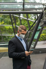 Photo of a young and attractive business man enjoying his coffee break outdoors. He is wearing smart clothes and is drinking in a reusable cup	