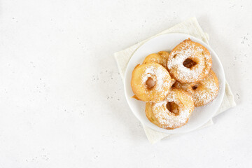 Homemade donuts with powdered sugar on white plate