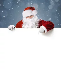 Foto op Canvas Happy Santa Claus pointing in blank white advertisement banner with copy space © rangizzz