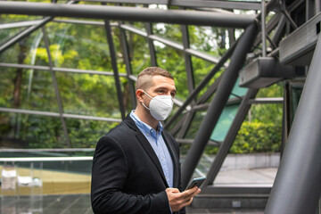 Photo of a young and attractive business man enjoying his coffee break outdoors. He is wearing smart clothes and is drinking in a reusable cup	