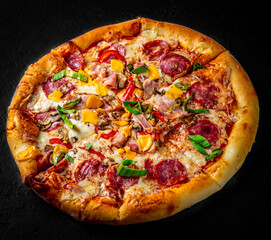 Pizza with Mozzarella cheese, salami, chicken meat, beef, ham, Tomato sauce, pepper, spices. Italian pizza on Dark grey black slate background