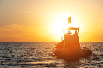 Tourist boat catamaran for hire of tourists with two sailors on board at sunset. Sea tourism on the...