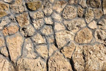 An uneven wall of decorative stacked cobblestones. Medieval background decorative insert