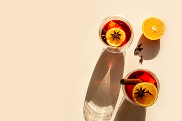 Two glasses of mulled wine, orange and spices on a white background. Contrasting shadows. Flat lay style