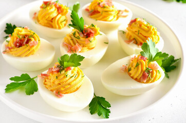 Deviled stuffed eggs with egg yolk, bacon, mustard and parsley