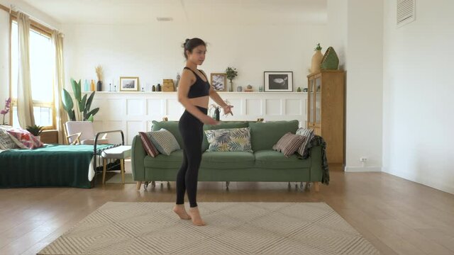 A young Indian Woman trains at home, Does a Spinning exercise, Bright Cozy Room, Dressed in a Black Top and Leggings. Sports Concept Healthy Life
