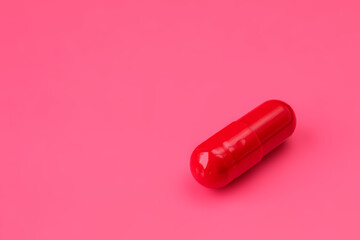 One red pill to increase potency on a red background. Men's health concept
