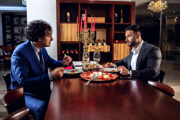 Two elegantly dressed men having dinner