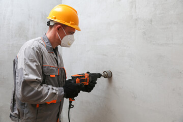 worker holds a hammer drill close-up on a gray wall background