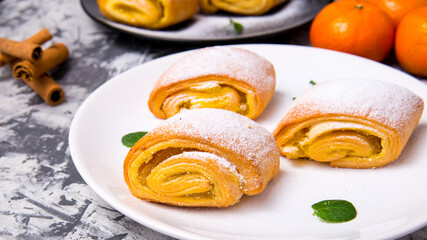 Strudel baking,powdered cake with Mandarin mint leaves,cinnamon sticks on a white,black plate on a black and white background with a space for text,side view