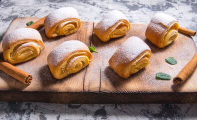 Baking strudel,rolls powdered with mint leaves tangerines,cinnamon sticks on a black and white background,on a wooden Board with a space for text,side view