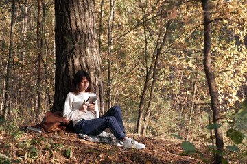 Beautiful young women reading a book sitting near a tree in a quiet place