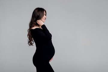 beautiful young pregnant woman on gray background in a photo studio