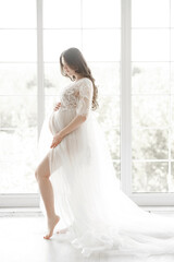 beautiful young pregnant woman in long white negligee