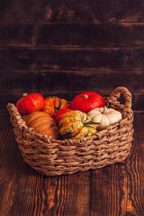 Basket with different varieties of pumpkin on a wooden background
