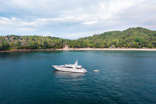 Large yacht and small boat in the blue Andaman Sea. Tropical ostrophe on background...