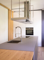 Modern kitchen with suspended hood, large sink, oven and wooden worktop