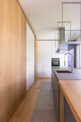 Modern kitchen with suspended hood, large sink, oven and wooden worktop.