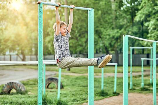 Strong kid doing hanging l-sit on sports ground