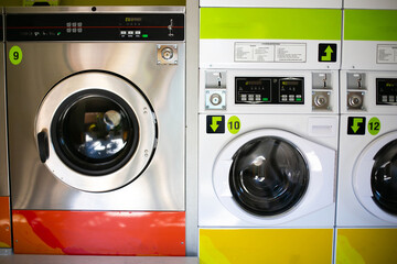 line of industrial washing machines in a public laundromat.