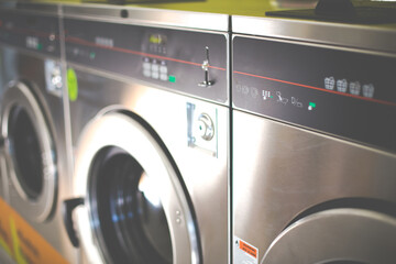 line of industrial washing machines in a public laundromat.