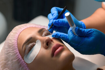 Eyelash care treatment procedures. Woman doing eyelashes lamination, staining, curling, laminating...