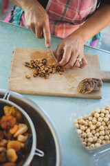 Young woman making Turkish dessert (asure) in the kitchen. Traditional Sweet Ashura, Ashura or Noah's Pudding. Woman cutting dried fruit for Ashura preparation.