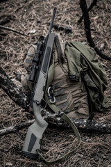 scout rifle lies on a backpack in the forest, survival rifle, soft focus