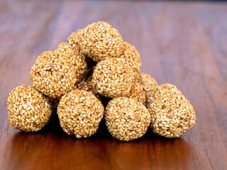 White sesame seed balls made with heated jiggery against wooden background