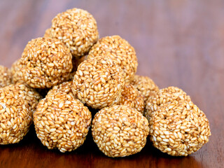 White sesame seed balls made with heated jiggery against wooden background