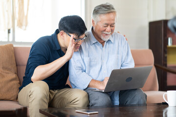 Obraz premium Senior Asian father and adult grown son having video call on laptop computer.