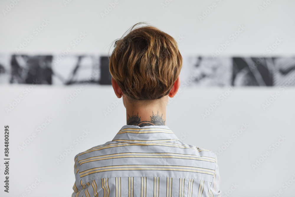 Wall mural graphic back view portrait of tattooed young woman looking at paintings at contemporary art exhibiti