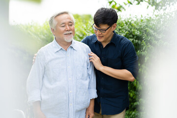Senior Asian Father With Adult grown Son hugging outdoors