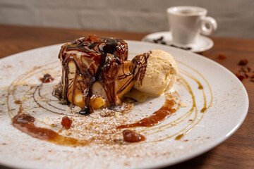 Serving pancakes with ice cream on the plate. Decorated with chocolate syrup and honey.
