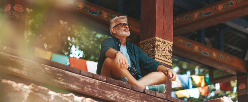 An elderly man with a beard meditates in a Buddhist temple. Peace and tranquility, satisfaction from silence.