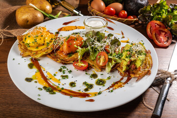 Potato pancakes with fried eggs, bacon and vegetables for breakfast.