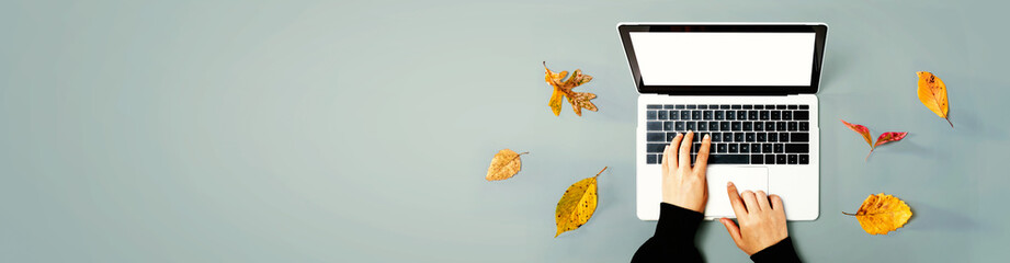 Obraz premium Autumn leaves with person using a laptop computer from above