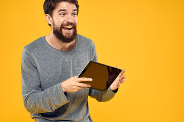 Emotional man with tablet in hands technology internet device lifestyle yellow background