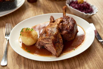 gebratene Ente im Ofen gegrillt mit Beilagen auf einem Holz Tisch in einem bayerischen Wirtshaus Biergarten  zu Weihnachten