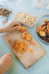 Young woman making Turkish dessert (asure) in the kitchen. Traditional Sweet Ashura, Ashura or Noah's Pudding. Woman cutting dried fruit for Ashura preparation.