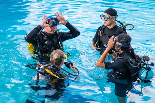 Diving instructor teaches how to attach the mask for students