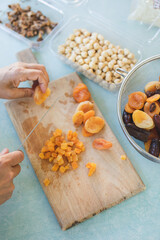 Young woman making Turkish dessert (asure) in the kitchen. Traditional Sweet Ashura, Ashura or Noah's Pudding. Woman cutting dried fruit for Ashura preparation.